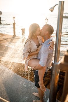 Happy couple by the sea. A guy and a girl are under the shower on an open-air pier. Happy couple on vacation. Man and woman by the sea.