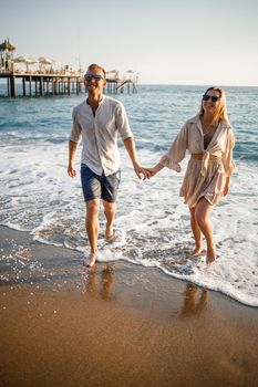 Happy couple by the sea. Honeymoon lovers. Man and woman on the island. Beautiful couple having fun on the seashore. Happy couple on vacation. Man and woman by the sea.