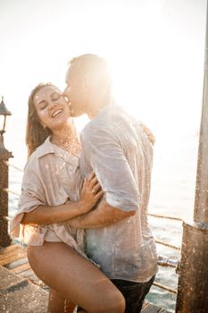 Beautiful couple in love hugs and kisses under the streams of water in a luxury spa hotel on their honeymoon, vacation in the tropics. Selective focus