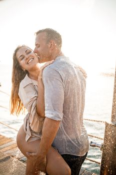 Beautiful couple in love hugs and kisses under the streams of water in a luxury spa hotel on their honeymoon, vacation in the tropics. Selective focus