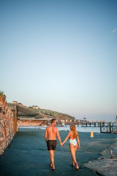 Romantic young couple in love walking together at sunset along the Mediterranean beach. Summer vacation in a warm country. Happy married couple on vacation in Turkey. Selective focus