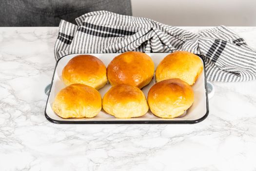 Freshly baked brioche buns on a metal serving tray.