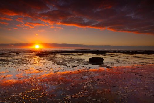 Seaside sunrise and vivid textured rock reflections in Royal National Park, Australia