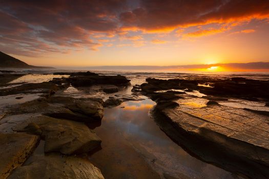 Beautiful sunrise over the ocean and  seashore with foreground rock pools