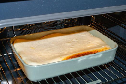 Cottage cheese casserole with raspberries and hazelnuts in a glass form is baked in the oven. Closeup. High quality photo