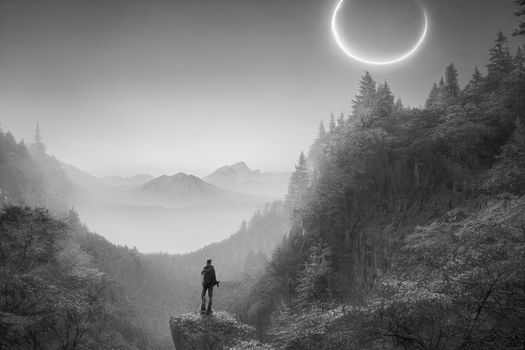 Intrepid traveler stands on cliff overlooking light autumn forest and  majestic light blue mountain range. 3D Render digital art.