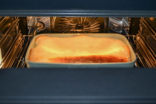 Cottage cheese casserole with raspberries and hazelnuts in a glass form is baked in the oven. Closeup. High quality photo