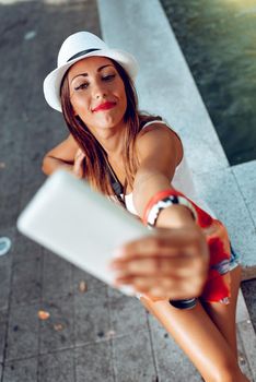 Top view on beautiful woman on vacation taking selfie with her smart phone. Selective focus.