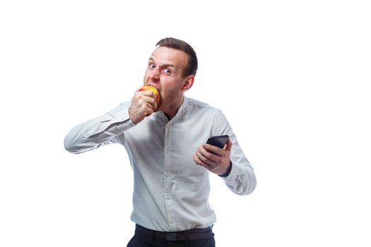Caucasian male businessman holding a mobile phone in black and holding a red-yellow apple. He is wearing a shirt. Emotional portrait. Isolated on white background