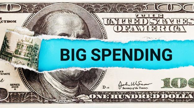 Words Big spending written on with American Dollar-bills. The word Big spending on dollar usa background. Concept of people enjoy spending time shopping in clothing stores offline.