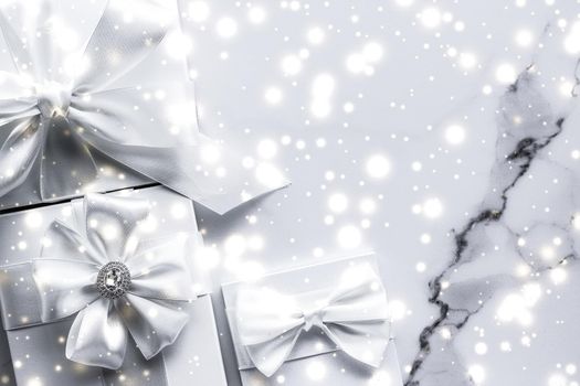 New Years Eve celebration, winter decoration and Valentines Day presents concept - Luxury holiday gifts with white silk bow and ribbons on marble background, Christmas time surprise