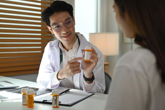 Smiling doctor explaining medicine dosage to o patient. Medicine, healthcare and people concept.