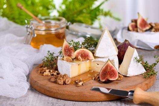 Brie cheese served on a wooden board with figs, walnuts and honey