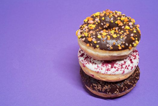 Macro shot of stack of donuts over purple background.