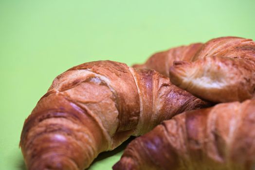 Macro shoot of croissants over green mint background.