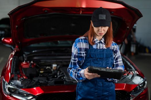 Caucasian female auto mechanic uses a special computer to diagnose faults