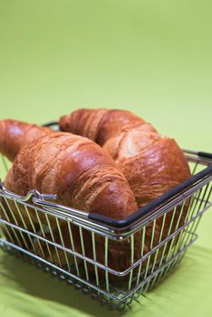 Macro shoot of croissants in shopping basket over green mint background