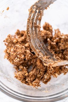 Mixing ingredients in a large glass mixing bowl to prepare cinnamon crumb topping.
