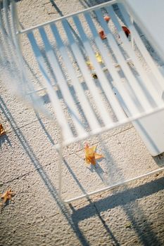 Yellow leaves lie on the tiles under the white chair. High quality photo
