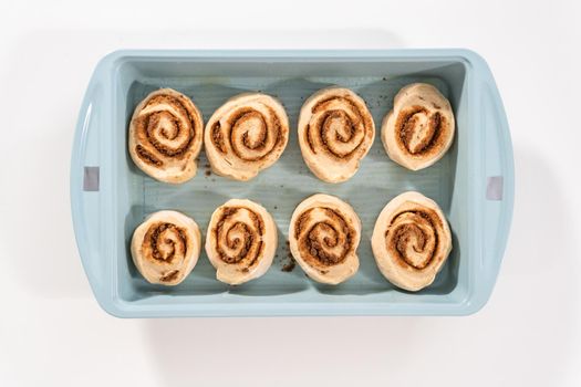 Unbaked cinnamon rolls in a blue baking pan.