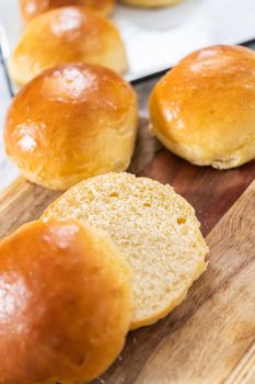Slicing freshly baked brioche bun on a wood cutting board.