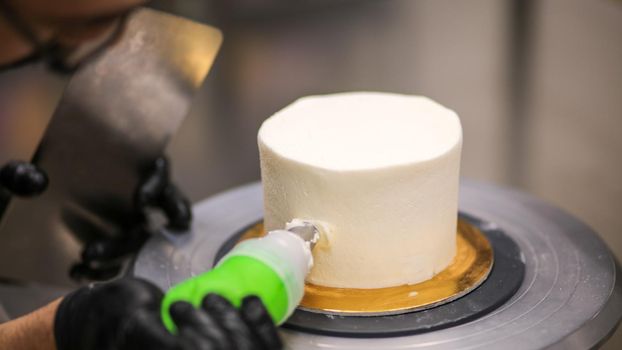 chef using using bag decorating a frosted icing cake