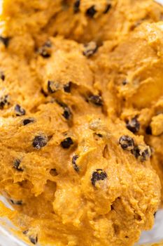Mixing ingredients in a large glass mixing bowl to bake chocolate pumpkin bundt cake with toffee glaze.