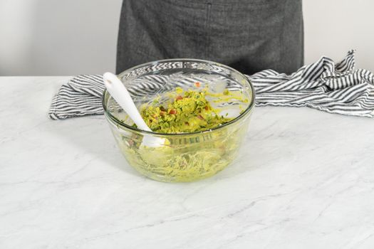 Cutting ingredients on a white cutting board to make classic guacamole dip.
