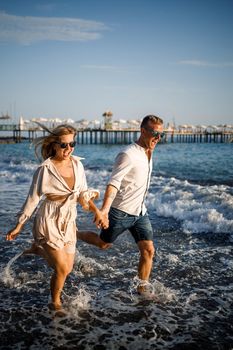 romantic young couple in love together on the sand walks along the beach of the Mediterranean sea. Summer vacation in a warm country.
