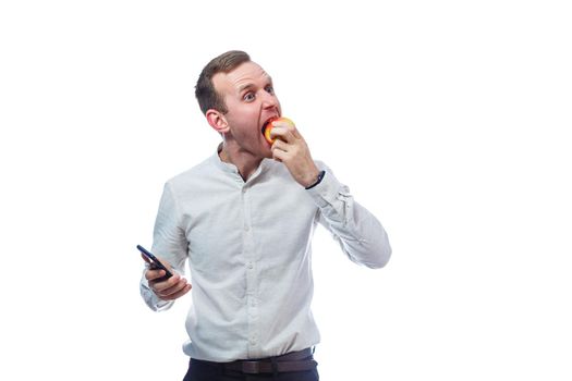 Caucasian male businessman holding a mobile phone in black and holding a red-yellow apple. He is wearing a shirt. Emotional portrait. Isolated on white background