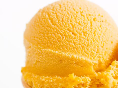 Scoop of gourmet pumpkin gelato in cake cone on white background.