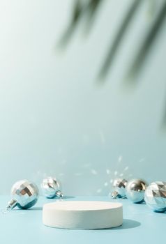 A minimalistic scene of a podium with christmas decorative balls and pine tree on a light blue background. Catwalk for the presentation of products and cosmetics. Showcase with a stage for products, mockup design, seasonal