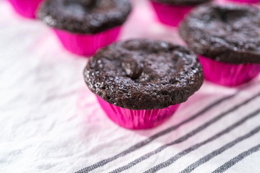Cooling freshly baked chocolate cupcakes on a paper towel.