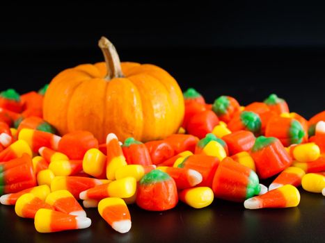 Halloween candy corn and pumpkin candies on black background.