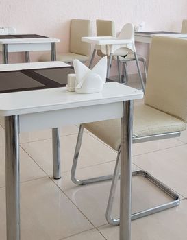 Stylish beige modern dining room interior with designer tables and chairs.