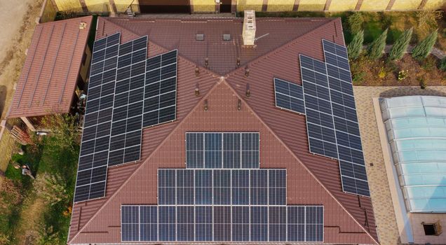 Row of blue solar panels on orange roof. Group of blue solar collectors with orange roof tiles.