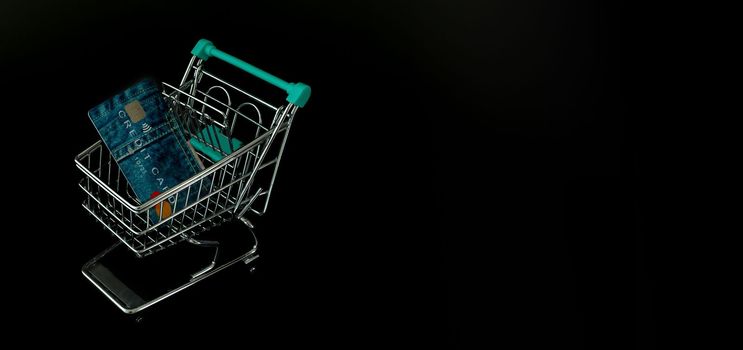 Black Friday advise with shopping trolley, credit card and black background.