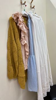 Close up of Clothes in blue, ochre, pink and white colour hanging on a hook ay home