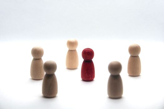 Wooden red figure surrounded by other figure on white background. Teamwork concept