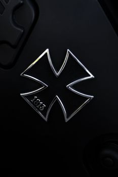 Metallic black German Maltese cross on the black matte tank of the motorcycle close up