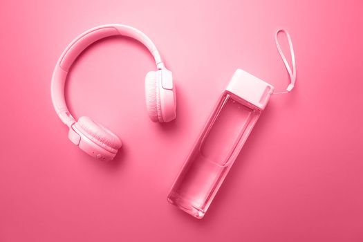 A sports water bottle and headphones lie on the background, the objects are painted in the color of the year 2023