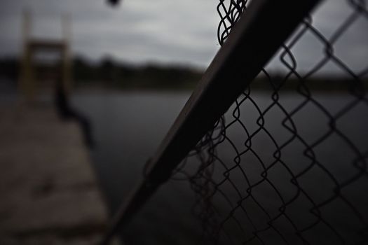 young teenage girl, lonely and renounced, alone with herself, thinking and bored, upset on the pier by the water, sitting on the pier in the evening, bored. High quality photo