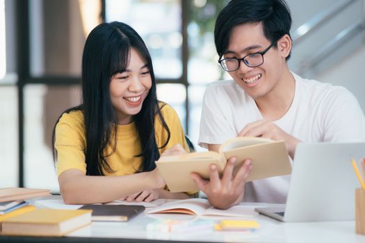 Young woman and man studying for a test or an exam. Tutor books with friends. Young students campus helps friend catching up and learning.