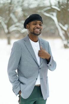 Proud african guy smile staying across snow in park Young man hold on jacket. High quality photo