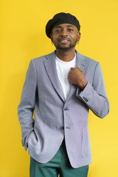 Cool man handsome isolated on yellow. Young african student holding suit and smiling in camera. High quality photo