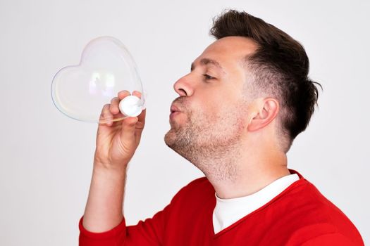 A man inflates soap bubbles in heart shape. Childhood memories concept