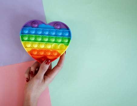 Woman holding antistress sensory colorful pop it toy, heart shaped
