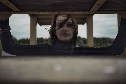 girl bullying loneliness by the water lake teenager alone in solitude trying isolation cope with anger and find strength in the evening gloomy photo abandonment thinking about fate is not easy and hard mooring at the pier. High quality photo