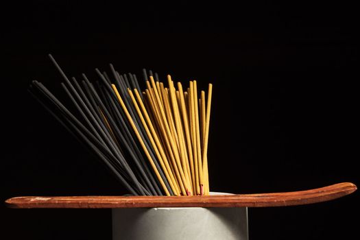 Many different incense sticks with wooden stand.