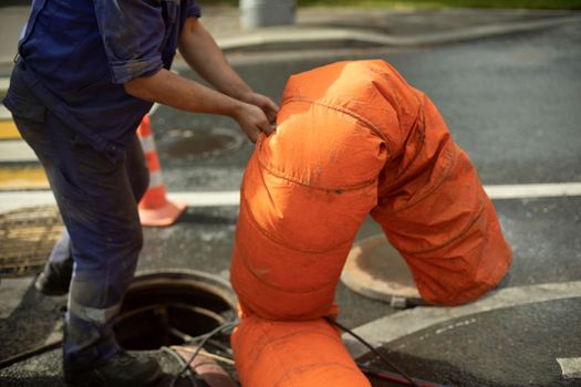 Sewer repair. Pumping waste from hatch. Open hatch. Worker controls air supply. Sewerage accident.